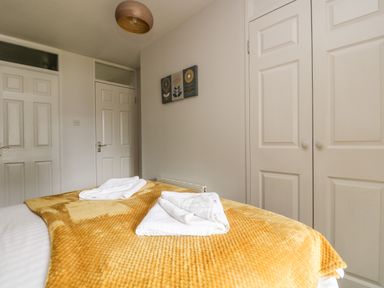 A bedroom with a bed covered in a yellow blanket and folded white towels on top at Devine Lodge in Callington