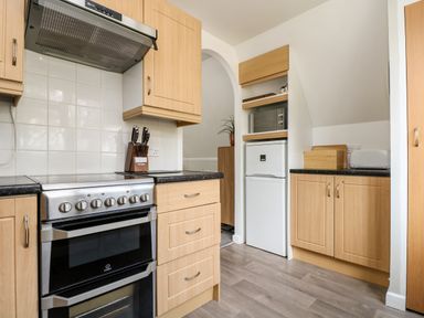 A kitchen with wooden cabinets a stainless steel stove a white refrigerator and a microwave at Devine Lodge in Callington