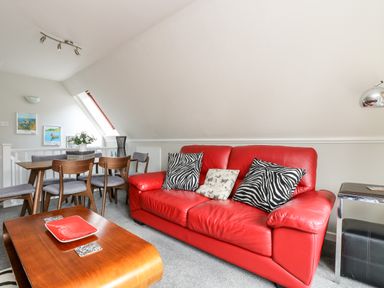 A living room with a red leather sofa and zebra print cushions at Devine Lodge in Callington