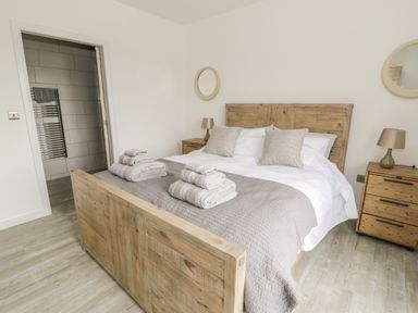 A bedroom with a wooden bed frame two bedside tables and lamps towels on the bed at Storws in Pentraeth
