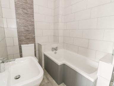 A bathroom with a sink toilet and bathtub with tiled walls at Storws in Pentraeth