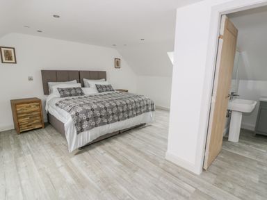 A bedroom with a bed side tables and an open door leading to a bathroom at Storws in Pentraeth