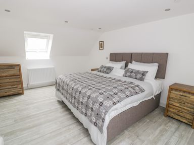 A bedroom with a double bed covered with a patterned bedspread two bedside tables and a chest of drawers at Storws in Pentraeth