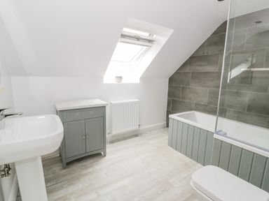 A bathroom with a bathtub sink toilet cabinet and a skylight window at Storws in Pentraeth