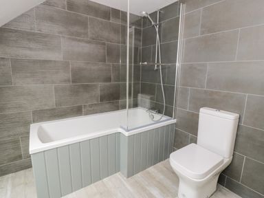 A bathroom with a bathtub shower and toilet at Storws in Pentraeth