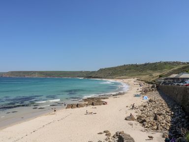 A sandy beach with people on it and hills in the background at Forge Cottage in Sennen