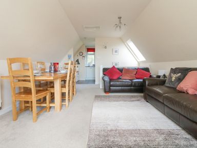 A living room with brown leather sofas and red cushions and a wooden dining table with chairs at Valley Lodge 44 in Callington