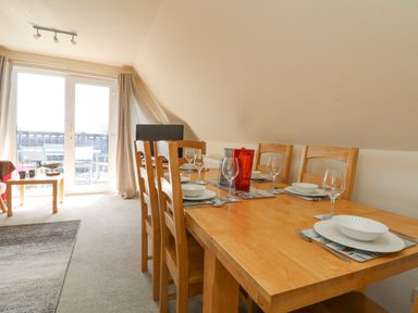 A dining area with a wooden table set for six and glass doors leading to an outdoor patio at Valley Lodge 44 in Callington