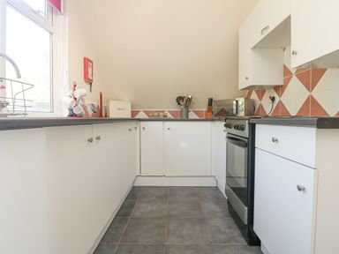 A kitchen with white cabinets a stove a microwave and utensils at Valley Lodge 44 in Callington