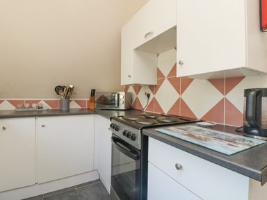 A kitchen with white cabinets black countertops an electric stove a microwave and kitchen utensils at Valley Lodge 44 Callington