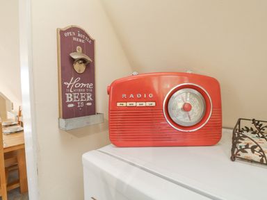 A red radio next to a wall-mounted bottle opener with a sign saying home is where the beer is at Valley Lodge 44 in Callington