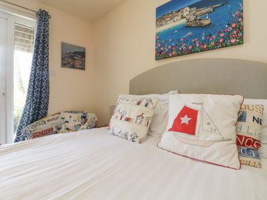 A bedroom with a bed with pillows and a chair near a window at Valley Lodge 44 in Callington