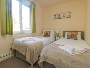 A bedroom with two single beds and a window with green curtains at Valley Lodge 44 in Callington