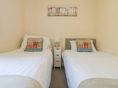 A bedroom with two single beds a small white nightstand and a lamp at Valley Lodge 44 in Callington