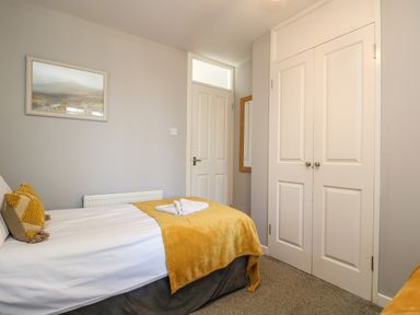 A bedroom with a bed with yellow pillows and blanket a closed door a white wardrobe and a wall mirror at Valley Lodge 58 in Callington