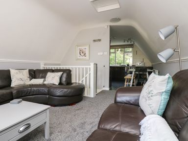 A living room with brown leather sofas and pillows next to a grey table and lamp at Valley Lodge 58 in Callington