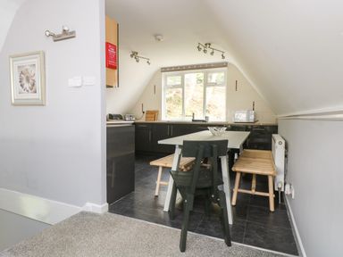 A kitchen area with a dining table and chairs under a sloped ceiling at Valley Lodge 58 in Callington
