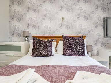 A bedroom with a double bed two purple pillows bedside tables and lamps at Valley Lodge 58 in Callington