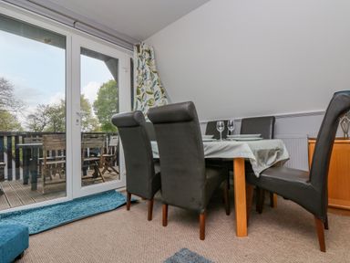 A dining area with a table set for four and black chairs next to glass doors leading to a balcony at Valley Lodge 5 in Callington