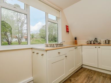A kitchen with white cabinets a sink a knife block and kitchen utensils on a wooden floor at Valley Lodge 5 in Callington