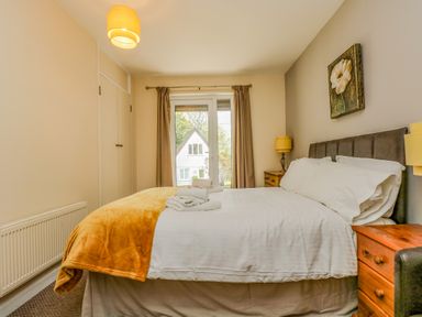 A bedroom with a bed with white linens and orange blanket and bedside tables with lamps at Valley Lodge 5 in Callington