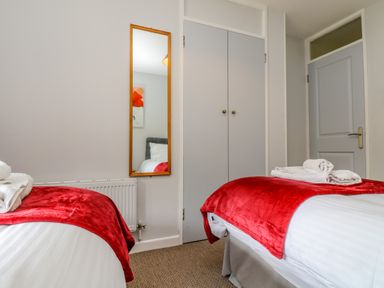 A bedroom with two beds with red blankets and folded towels a mirror wardrobe and a door at Valley Lodge 5 in Callington
