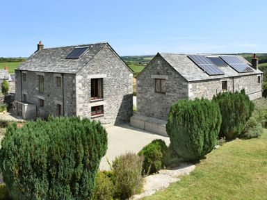 Two stone houses with solar panels on the roofs and green shrubs in front at Marhayes in Camelford