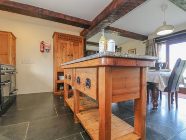 A kitchen with a wooden island and dining table with chairs at Marhayes in Camelford