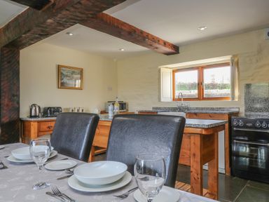 A kitchen with wooden furniture black chairs and a dining table set with white dishes at Marhayes in Camelford