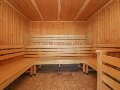 A wooden sauna room with benches along three walls and tiled floor at Marhayes in Camelford