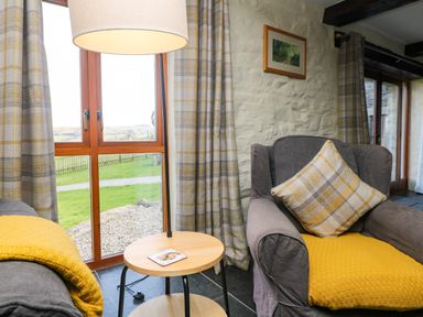 A living room with a gray armchair and gray sofa with yellow throws and curtains at Marhayes Camelford
