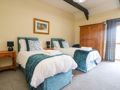 A bedroom with two single beds wooden wardrobes and bedside tables at Marhayes in Camelford