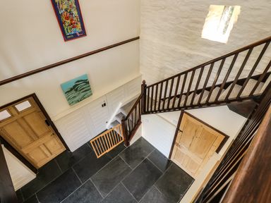 A staircase with wooden railings and doors in a hallway at Westhayes in Camelford