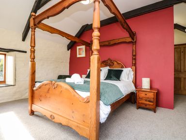 A bedroom with a wooden four-poster bed bedside table and window at Westhayes in Camelford