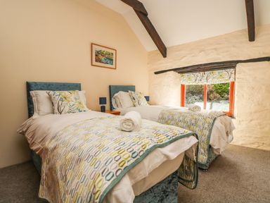 A bedroom with two single beds with patterned blankets and floral pillows at Westhayes in Camelford