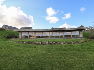 A modern single-story building with large glass windows on a grassy hill at Westhayes in Camelford