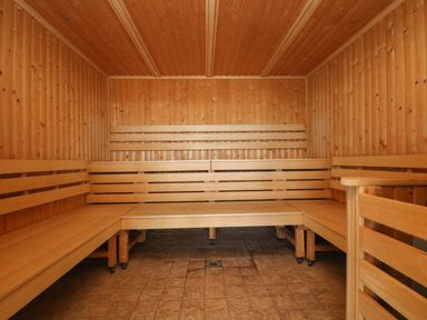 An empty wooden sauna room with benches along the walls and a tiled floor at Westhayes in Camelford