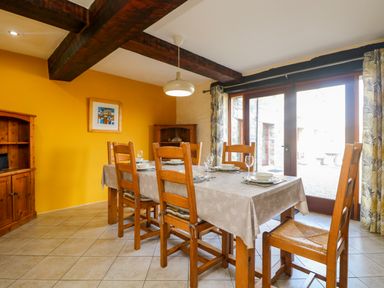 A dining room with a wooden table and chairs set with plates and glasses next to large glass doors at Westhayes in Camelford