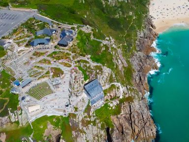 A coastal amphitheater with tiered seating next to cliffs and a sandy beach at Kerensa ha-Kres in Sennen