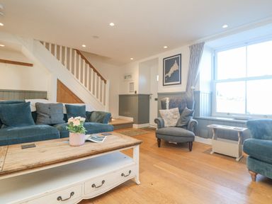 A living room with blue sofas a wooden coffee table and a window at Bal View in St Just
