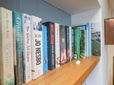 A wooden bookshelf with various books neatly arranged at Bal View in St Just