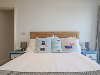 A bedroom with a wooden headboard a bed with decorative pillows and two blue nightstands with lamps at Bal View in St Just