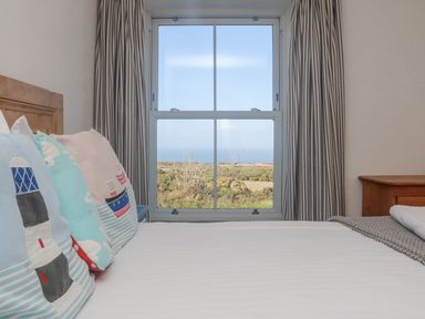 A bedroom with a bed near a window showing a landscape at Bal View in St Just