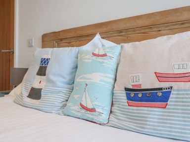 A close up of three decorative pillows with nautical designs on a bed at Bal View in St Just