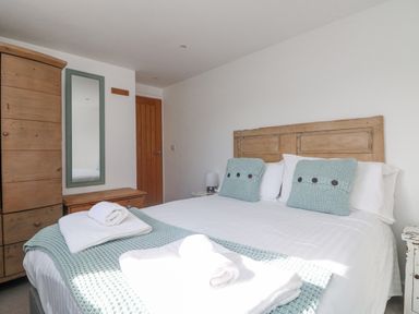 A bedroom with a wooden bed frame and blue cushions on the bed at Bal View in St Just