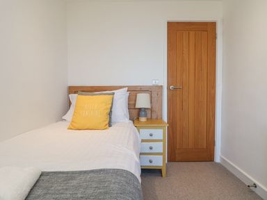 A bedroom with a single bed with pillows and a bedside table with a lamp at Bal View in St Just