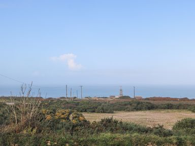 A coastal landscape with shrubs and utility poles near the sea at Bal View in St Just