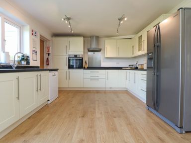 A kitchen with white cabinets stainless steel refrigerator oven and wooden floor at Penhaven in Crackington Haven