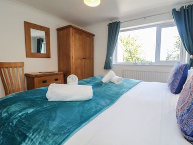 A bedroom with a bed covered by blue blanket and white towels by the window at Penvhaven in Crackington Haven