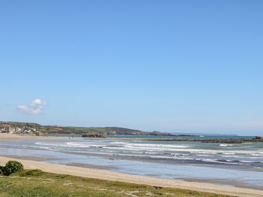 A beach with waves and people in the water near a coastal village at Mackerel Sky in Marazion